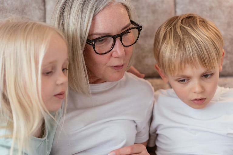 A grandparent and her grandchildren enjoy quality time together indoors.