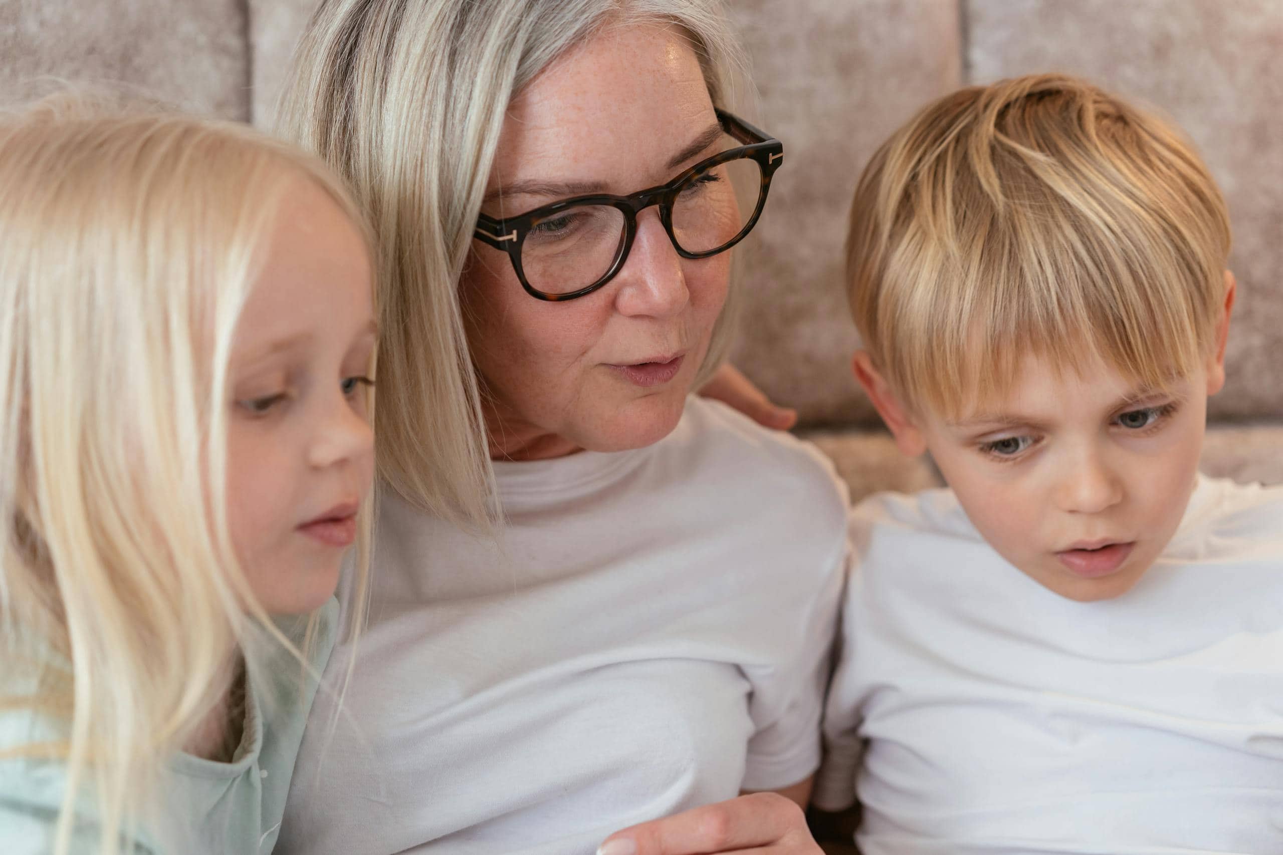A grandparent and her grandchildren enjoy quality time together indoors.
