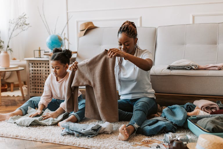 A warm moment of a mother and daughter folding clothes together on the living room floor.